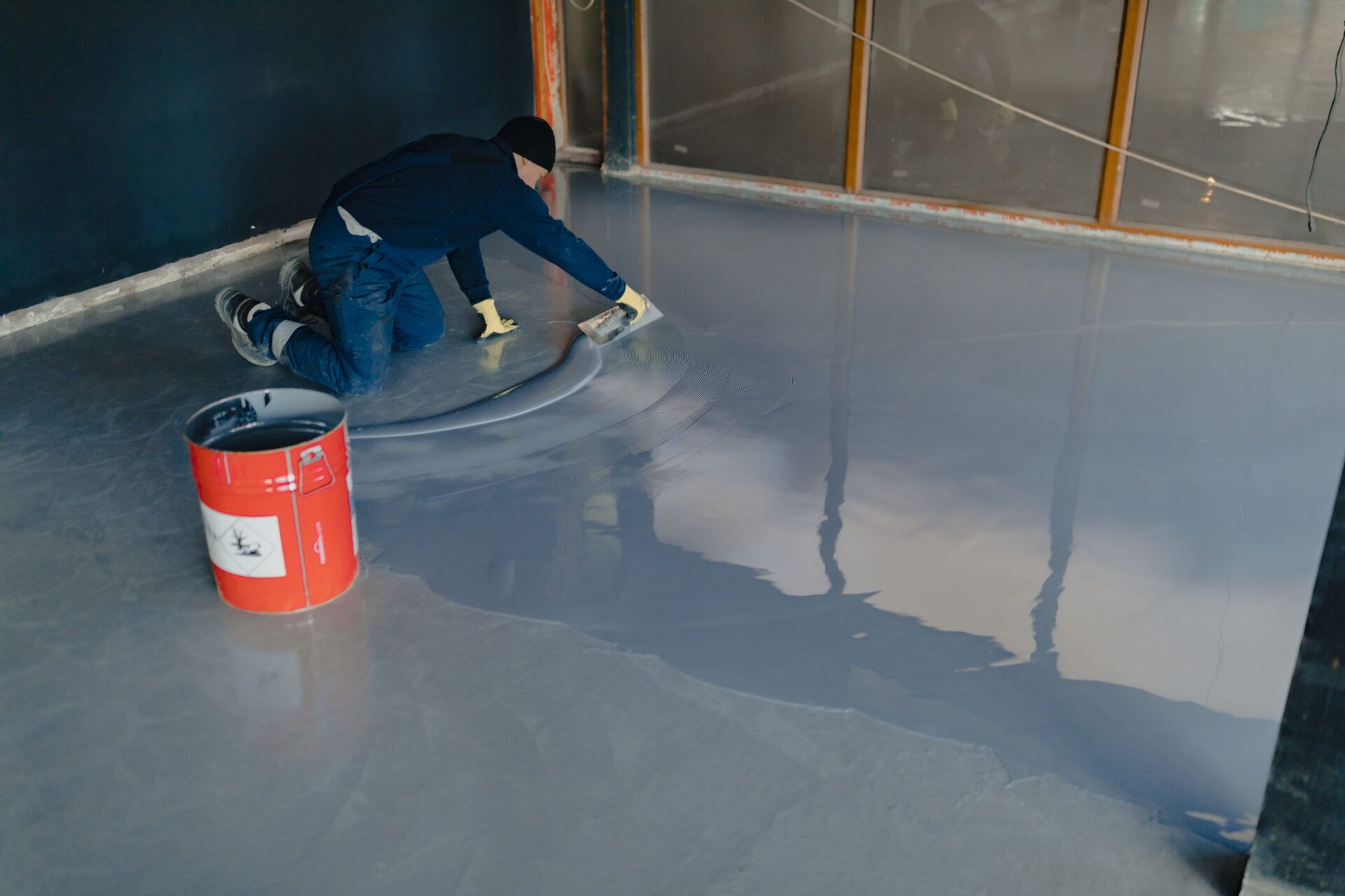 The worker applies gray epoxy resin to the new floor